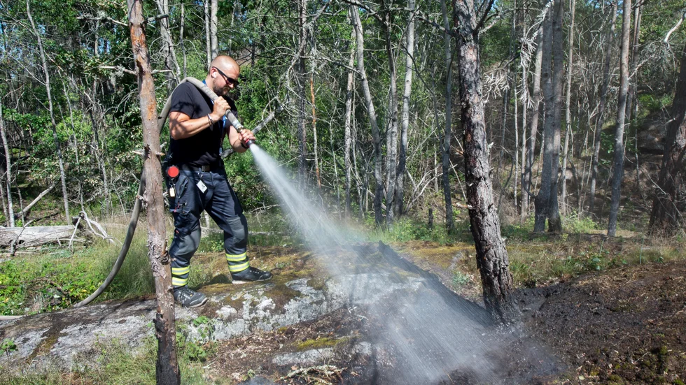Patrik Nyman släcker markbranden i skogen bakom vårdcentralen vid Tomtaklintgatan i Trosa på onsdagen.