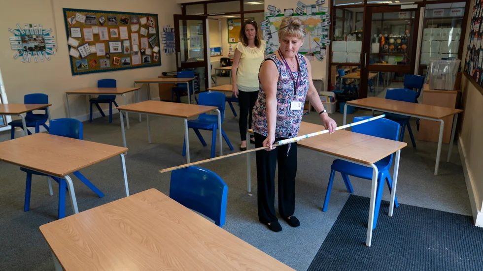 Jane Cooper, lärare i sjätte klass, kontrollerar avståndet mellan skolbänkarna i sitt klassrum i skolan Lostock Hall i Poynton i närheten av Manchester.