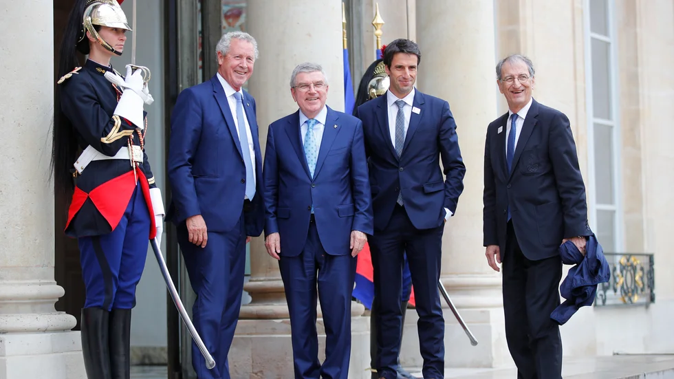 Guy Drut, här till vänster om IOK-ordföranden Thomas Bach, i mitten, menar att OS i Paris 2024 måste anpassas till den nya verklighet coronapandemin orsakat. Arkivbild.