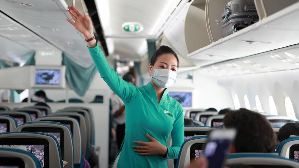Flygvärdinna med skyddsmask instruerar passagerare på flygplan i Ho Chi Minh-staden i Vietnam. Arkivbild.