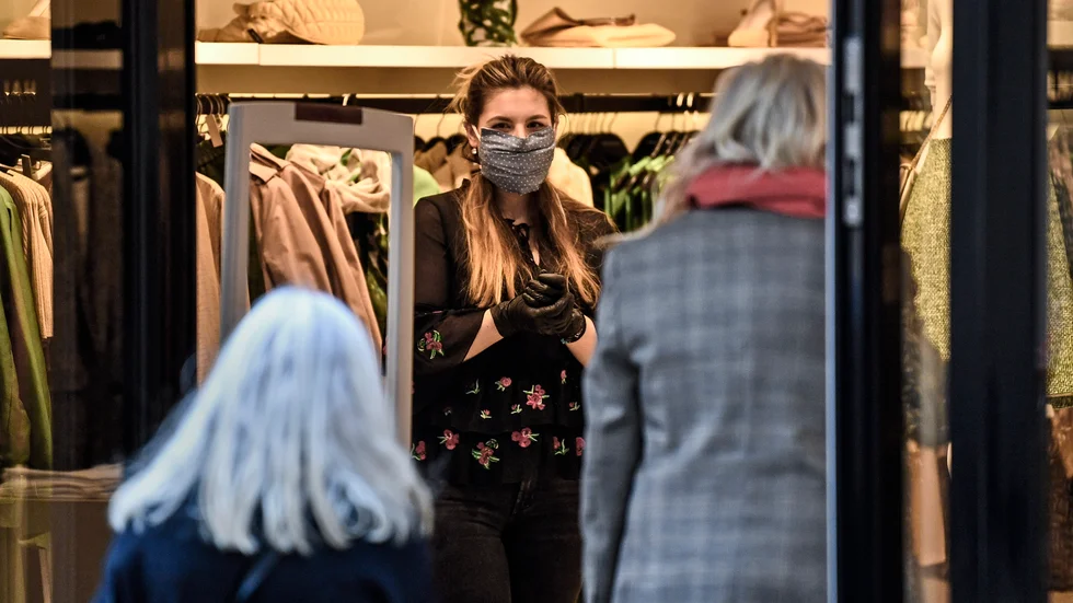 En butiksanställd tar emot en kund i en mindre butik i Essen i västra Tyskland den 20 april. Mindre butiker har sedan tidigare tillåtits att hålla öppet.