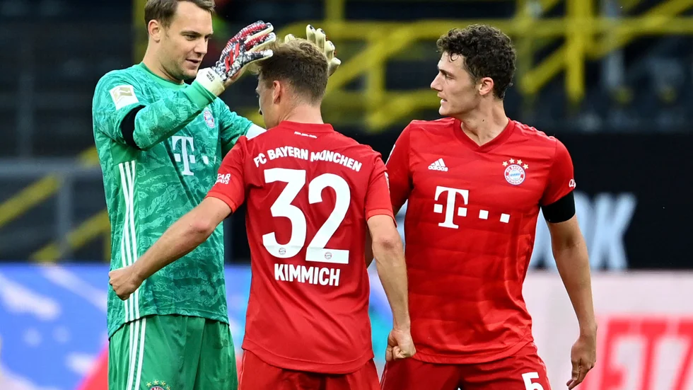Bayern Münchens Joshua Kimmich, mitten, kramas om efter att lobbat in segermålet borta mot Dortmund.