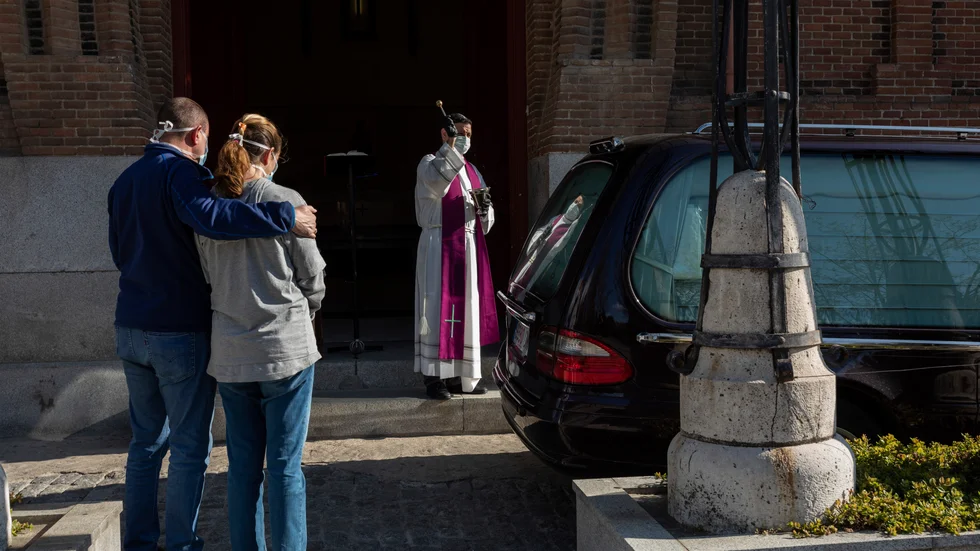 En präst genomför en begravningsceremoni på en av Madrids kyrkogårdar.
