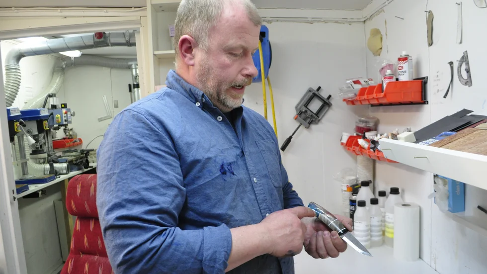 Patrik i verkstan bakom villan i Jokkmokk bland knivämnen, färger och maskiner. 