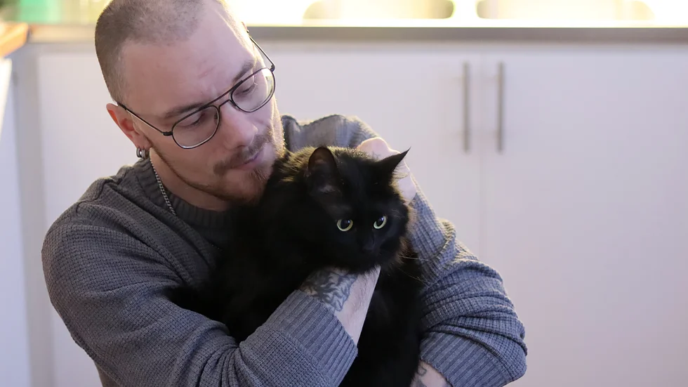 Jhonny Backman kopplar av i familjens kök tillsammans med katten Siri.