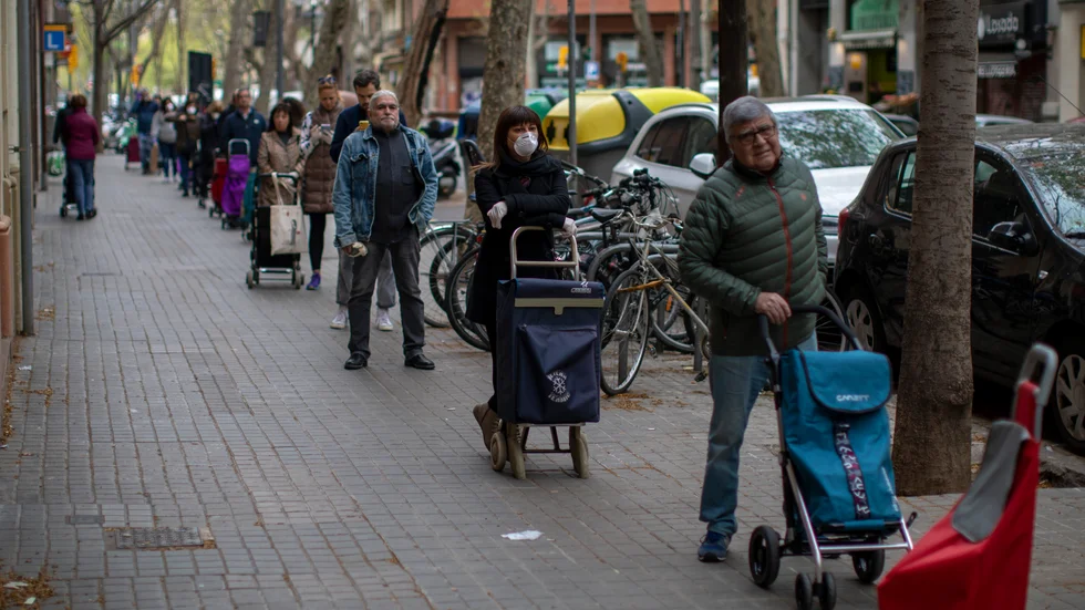 Människor i Barcelona, Spaniens näst största stad, köar på behörigt avstånd från varandra för att få handla mat på fredagen.
