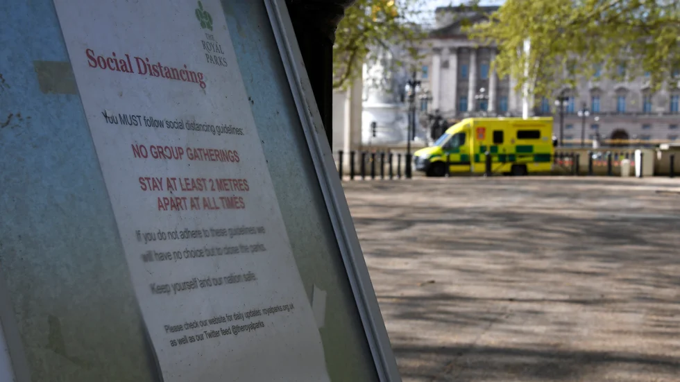 En skylt om att hålla avstånd till andra uppsatt i en park i London.