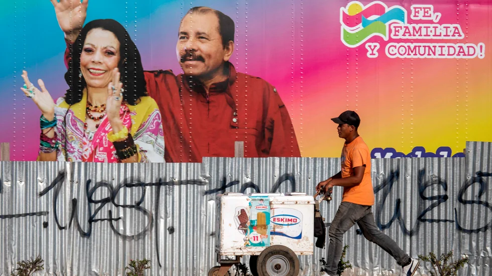 En glassförsäljare går förbi en mobil vårdinrättning med ett portträtt av Nicaraguas president Daniel Ortega och hans fru, vicepresident Rosario Murillo.