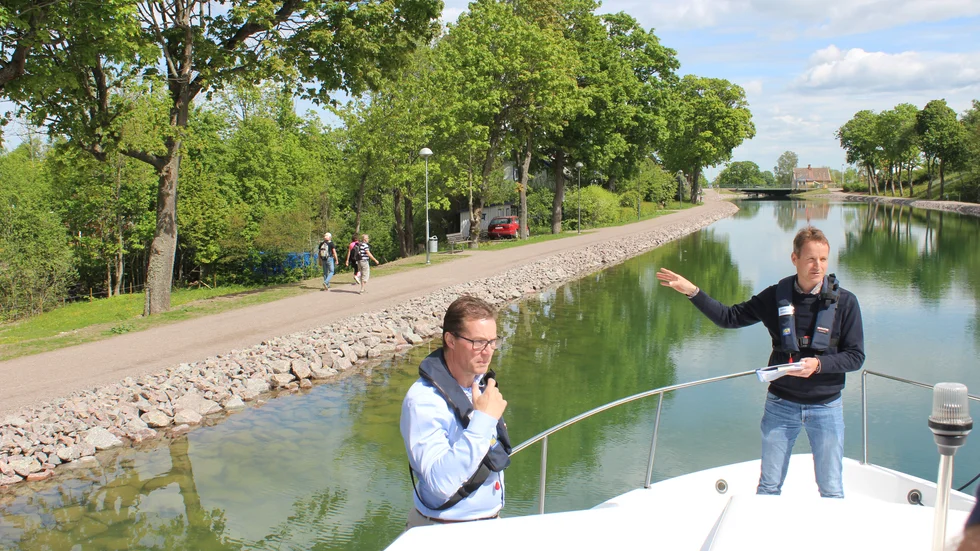 Från den eldrivna båten pekar Göta kanalbolags anläggningschef Stefan Ljungblad ut var det omfattande arbetet med att täta läckorna genomförts. Till vänster bolagets vd Roger Alsäter.