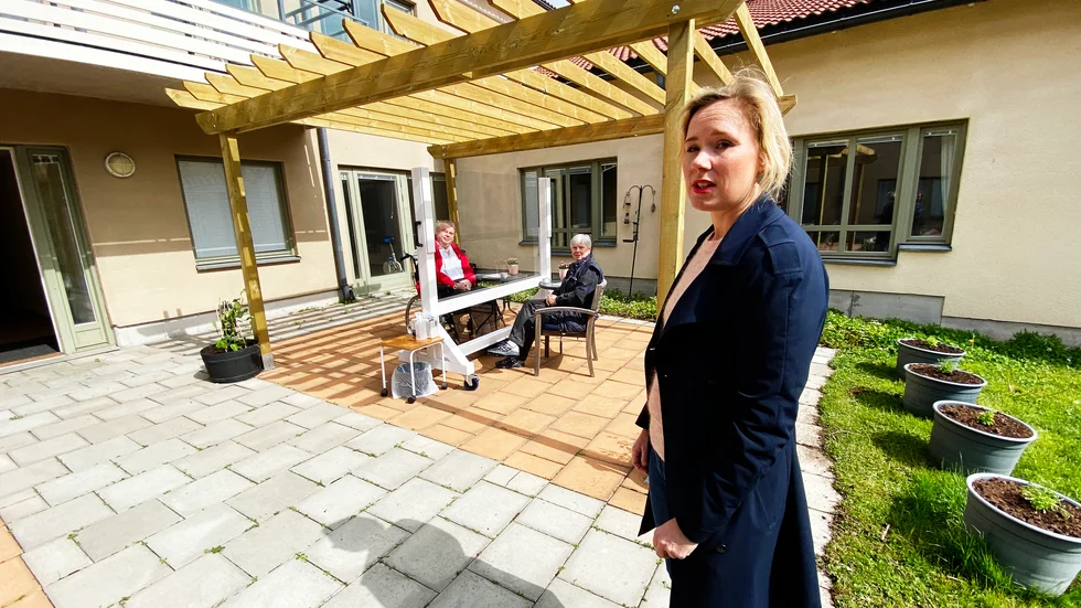 Caroline Hoffstedt (S) vid Höganäs äldreboende. I bakgrunden Svante och Ewa Wallner som den 18 maj träffades med en plexiglasskiva som virusskydd mellan sig. 