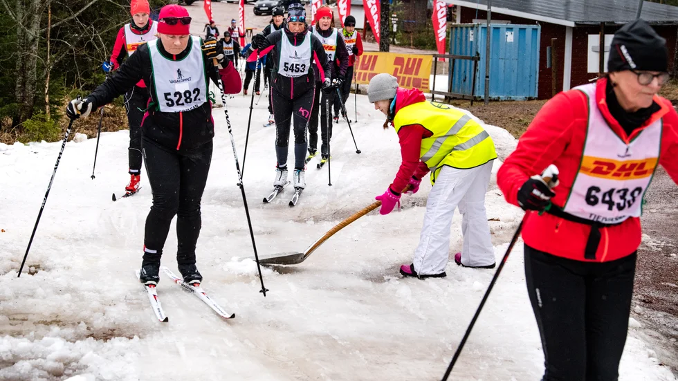 Skidåkarna i Tjejvasan passerar kontrollen i Eldris där en funktionär skottar i mera snö. Årets Tjejvasan går till historien som den blötaste på länge. 