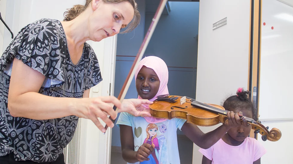 Kultur och idrott ges stort utrymme i Lyckliga gatornas aktiviteter. På denna bild från 2018 får Siham och Suheyla Ibrahim prova att spela fiol med hjälp av Musikens hus-akademiens Ingrid Falk.