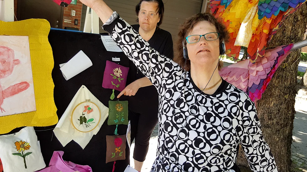 Lotta Svantesson har broderat fina saker. I bakgrunden hjälper Elvira-Märta Pettersson till och pekar.