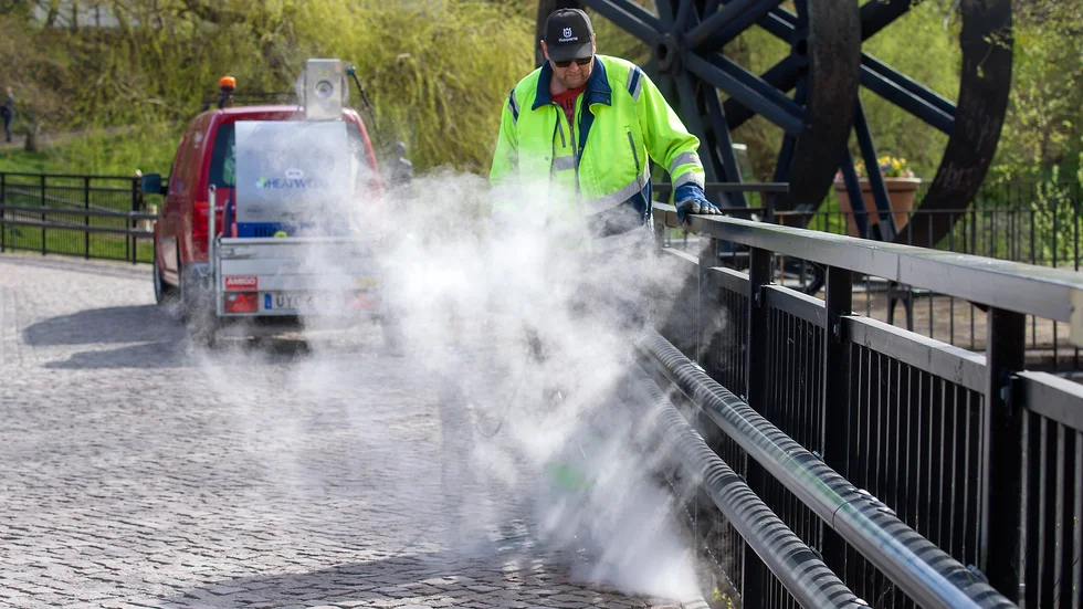 Göran Karlsson, jobbar som parkarbetare åt Nyköpings kommun, rensar ogräs vid Stohusqvarn med hetvatten.