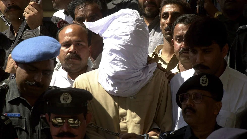 En person med täck ansikte, enligt polisens uppgifter Ahmed Omar Said som dömdes för mord på den amerikanske journalisten Daniel Pearl, förs in i rättegångssalen i Karachi i Pakistan 26 februari 2002.