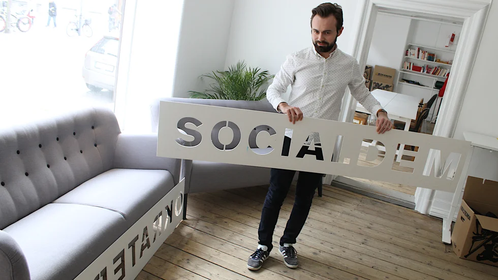 Linus Emmoth, ombudsman för Socialdemokraterna i Norrköping, visar schablonen genom vilken den nya lokalen på Gamla Rådstugugatan ska märkas upp utvändigt. 