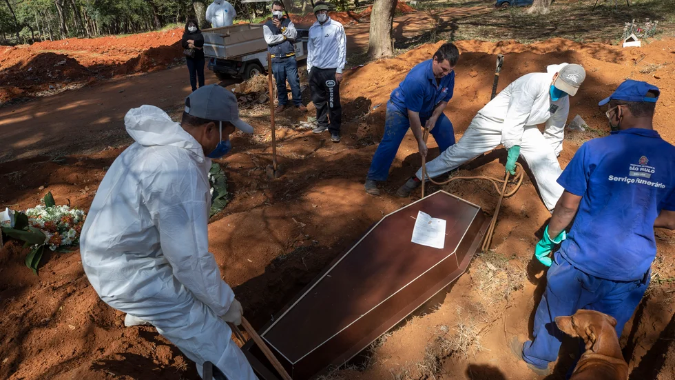 Kyrkogårdsarbetare begraver människor som avlidit till följd av covid-19 i São Paulo i Brasilien.