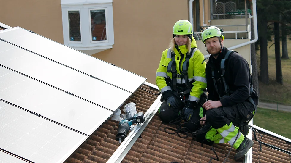 Tora Finnberger och Robert Wieland monterar solcellspaneler på taket till fastigheten på Skolgatan. 