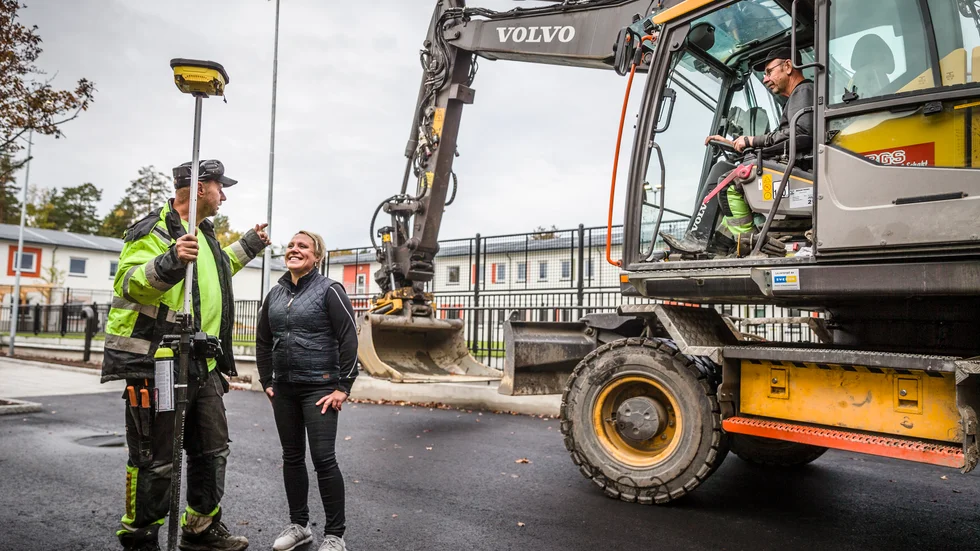 Anläggaren Bosse Karlsson i samspråk med Trädgårdsanläggare Hallbloms vd Malin Persson vid bygget av den nya skolgården vid Gottsundaskolan. I bakgrunden grävmaskinisten Anders Bergström.