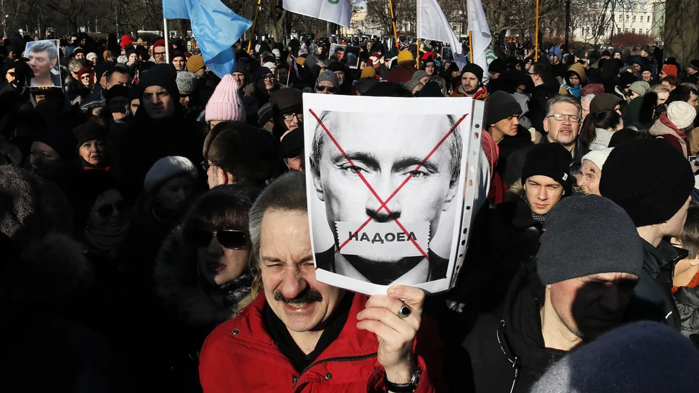 En demonstrant håller upp en bild på Vladimir Putin med texten "Trött på" under demonstrationen i S:t Petersburg.