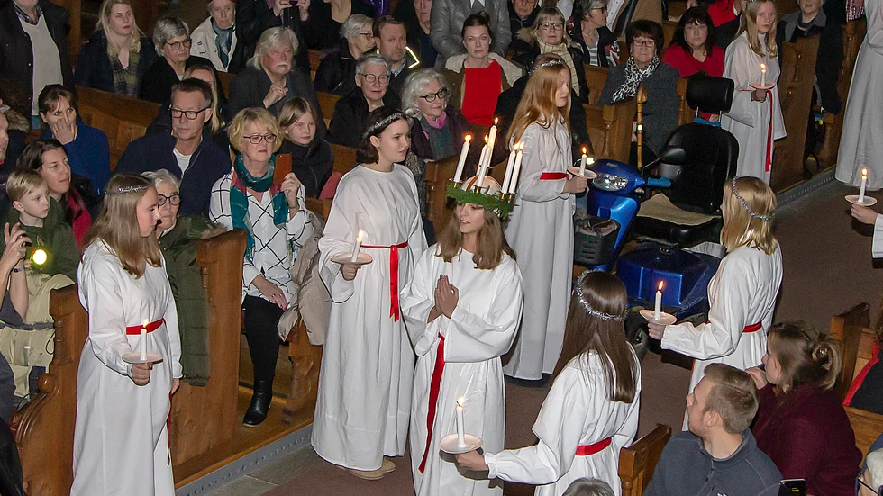 Vadstenas lucia Stina Holmstedt skrider fram i kyrkans mittgång, eskorterad av sina tärnor.