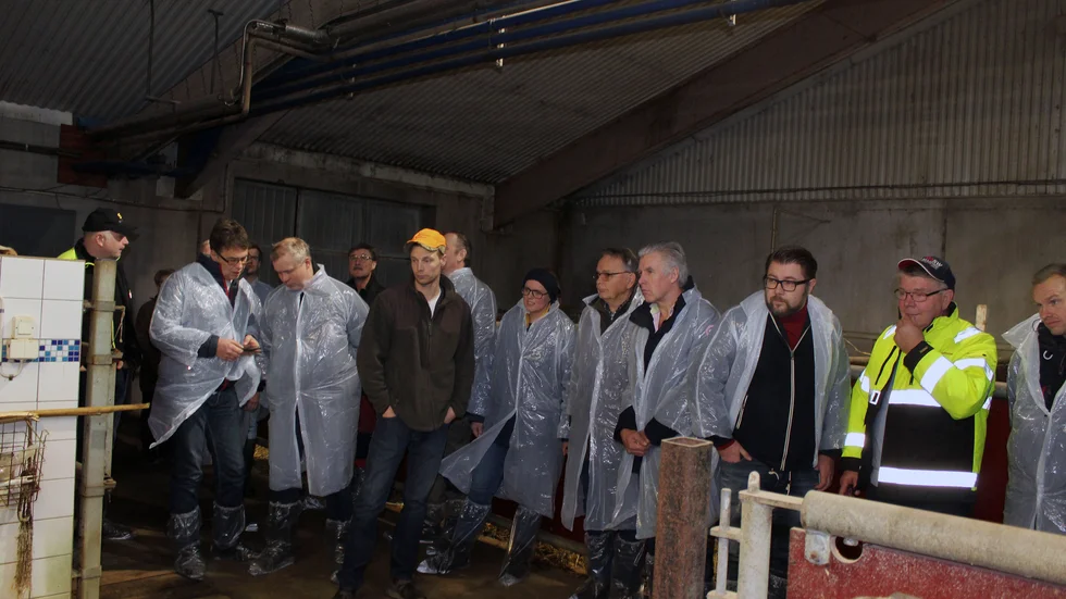 Lantbrukare, politiker och tjänstemän begrundar mjölkrobotens arbete. På bilden ses bland andra Fredric Hellner (orange keps) och hans pappa, Thomas Hellner (reflexjacka).