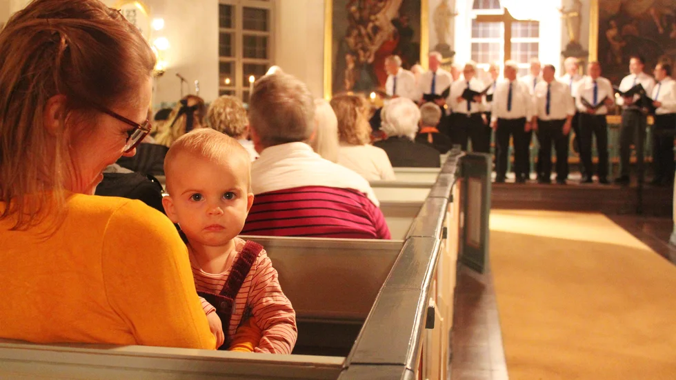 Eva-Karin Dahlberg med barnbarnet Emelinn Larsson, 1 år i famnen. Emelinn tycker att manskören låter lika bra i alla riktningar.