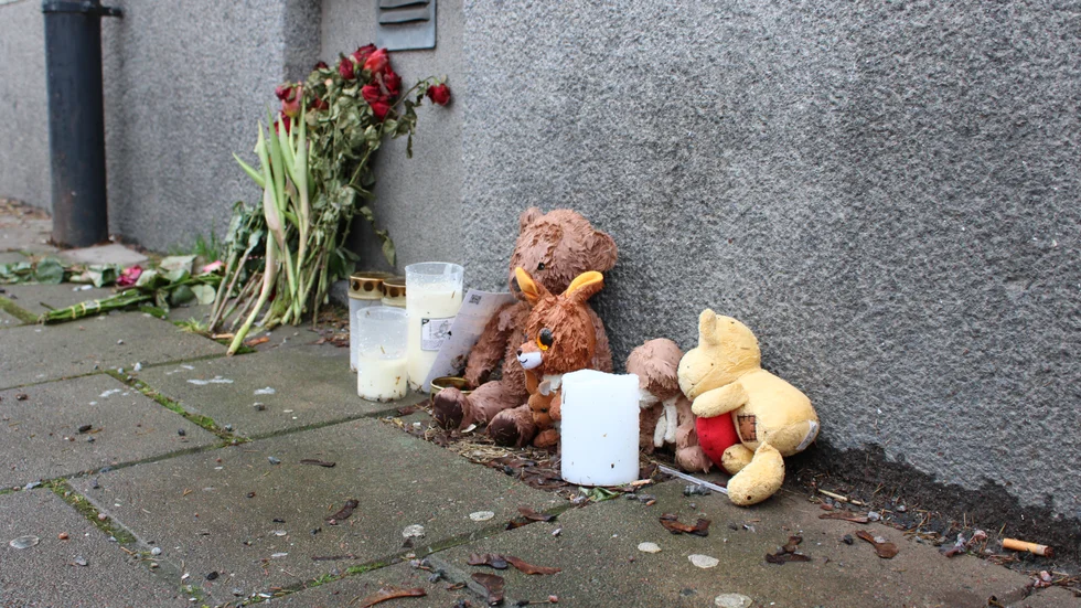 Utanför porten i centrala Norrköping där treåringen bodde, ligger fortfarande blommor, nallar och ljus.