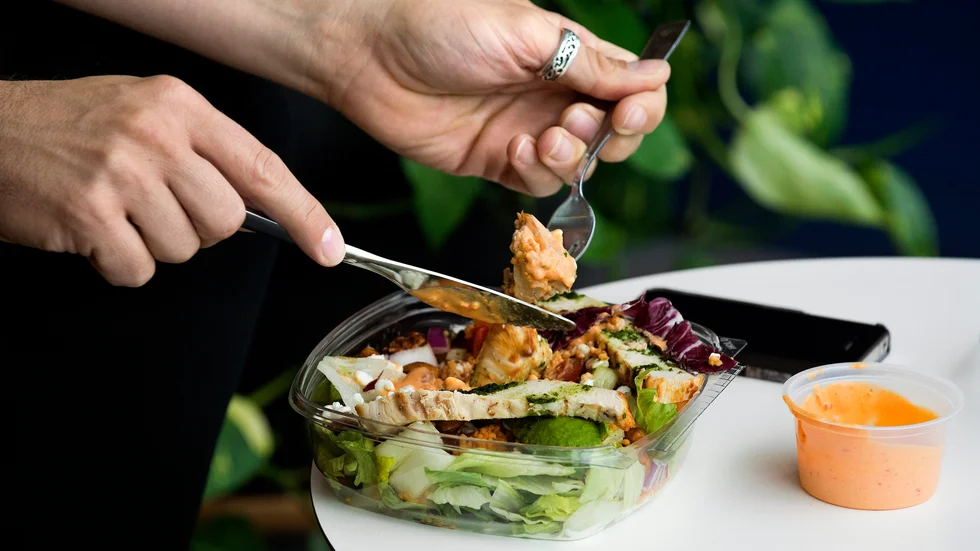 En person som njuter av en kycklingsallad på en restaurang. 