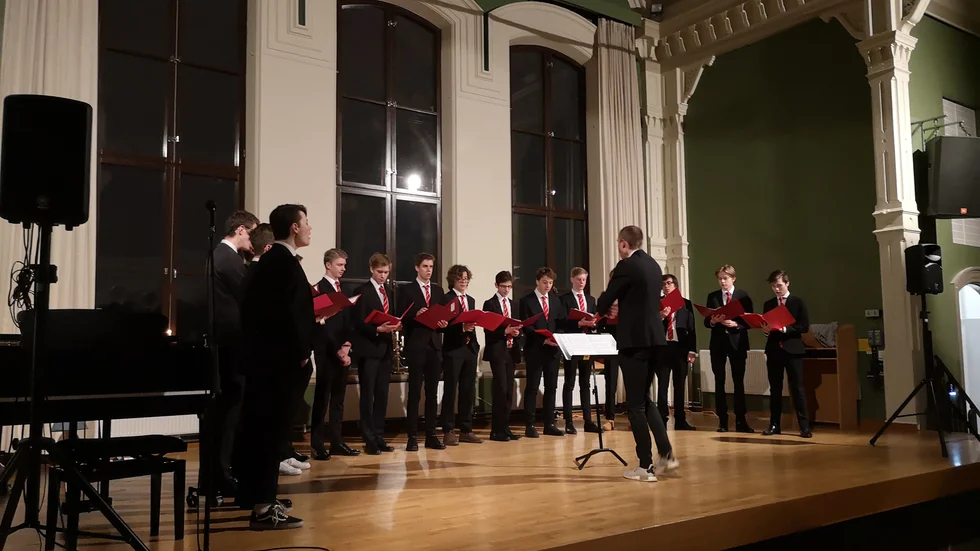 Katedralskolans manskör repeterar i mörk kostym inför julkonserten.