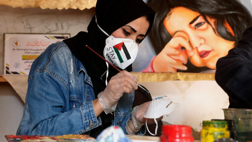 Den palestinska konstnären Samah Saed dekorerar en ansiktsmask för att få fler att bära ansiktsmask i Gaza. Arkivbild.