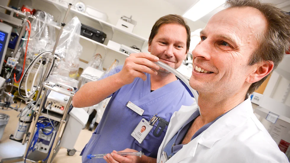 Fredrik Holmner visar på kollegan Fredrik Nyström hur ecmo-maskinen kopplas in i kroppen. I bakgrunden syns själva maskinen. Arkivbild.