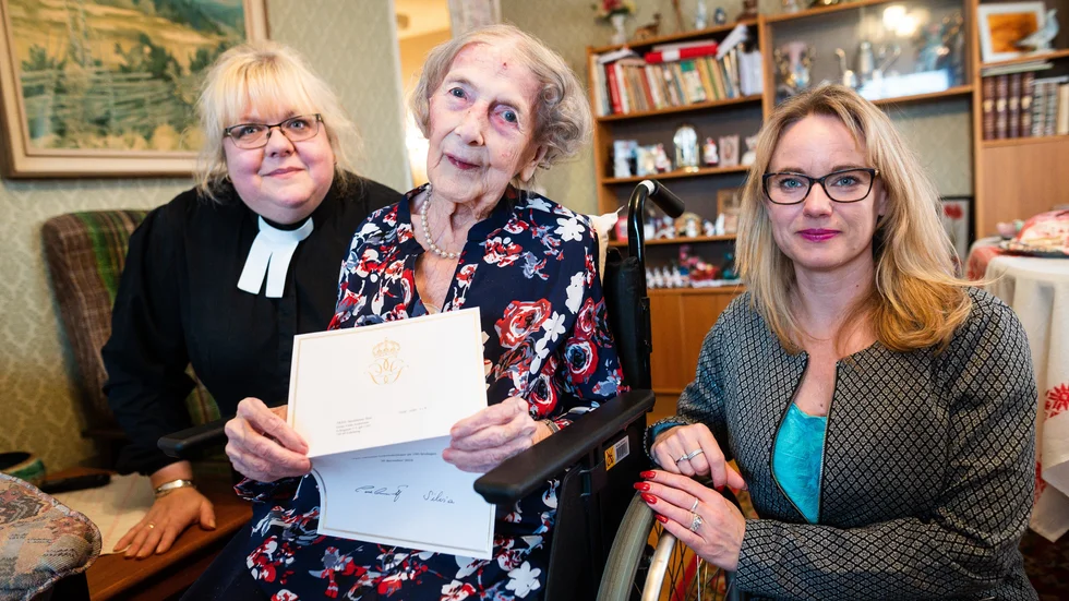 Prästen Maria Lund och kommunalrådet Ulrika Ornbrant (C) besökta hundraåringen Greta Andersson på måndagen. Greta visar upp sitt telegram som både kungen och drottningen skrivit under.  