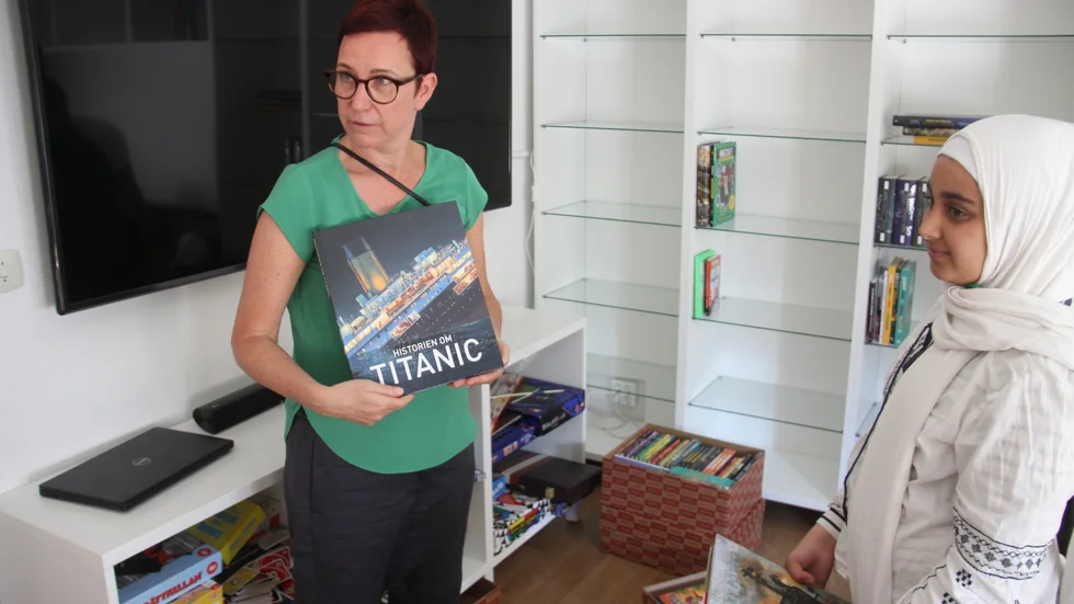 Helena Gille, bibliotekarie och samordnare på kommunen, visar Alaa en bildboksversion av Titanic.  