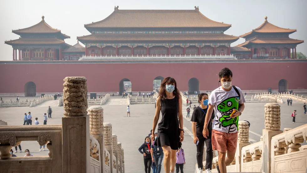 Besökare med munskydd vid Förbjudna staden i Peking under fredagen.