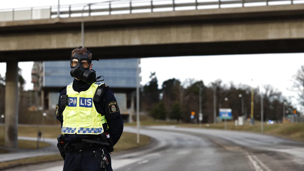 Polis i gasmask vid Säkerhetspolisens högkvarter i Solna norr om Stockholm.