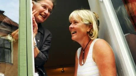 Ulrike Jansson och Yvonne Johansson tittar ut genom fönstret på Wimmerströmska gården.