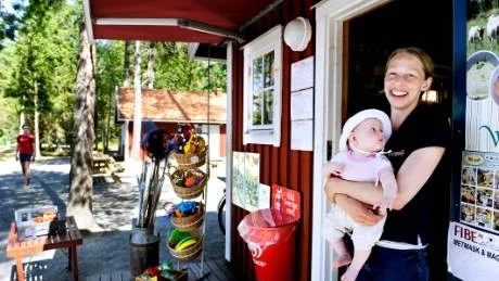 Lina Johansson och dottern Edith i entrén till hennes butik på Hasselö. Lina tycker bara att det finns fördelar med nya hyresrätter på ön.