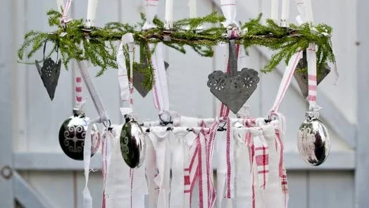Ljuskrona med inspiration från forna tiders feststänger. Dekorera ringarna med lummer, julgranskulor och gammeldags levande ljus.