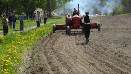 Anders Kasselstrand dirigerar traktor med konstgödselspridare av äldre modell.