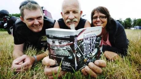 Anders Berg och Jan Nilsson delar ut "Biker-bibeln" under MC-dagarna. De är medlemmar i den kristna mc-klubben "Holy Riders". Marie Berg (längst till höger) är inte med i klubben, men är gift med Anders och har följt med honom till Västervik bak på hans båge. Foto: Ellen Nielsen-Kindstrand
