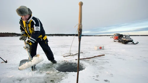 Med hjälp av en spade ser Ulf Lindgren till att hålet blir fritt från is och snö.