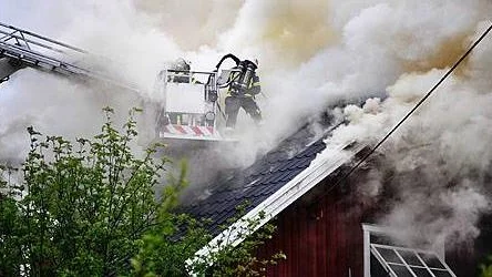 Räddningstjänsten försöker släcka det brinnande taket med hjälp av skärsläckare.