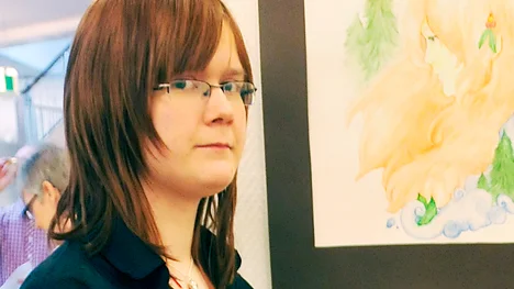 Emma Johansson vid några av sina målningar som just nu finns att se i konsthallen i biblioteket.