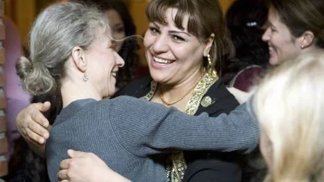 Fatima Amiri, i sin traditionella Afghanska dräkt i guld och svart, kramar om Ylva Håkansson på knytkalaset i Hertsökyrkan. FOTO: Pär Bäckström
