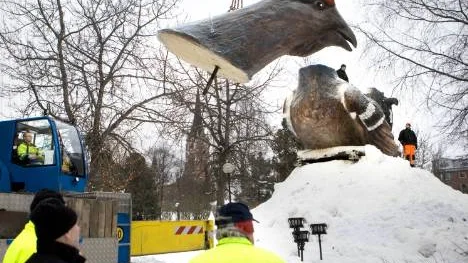 Det 500 kilo tunga huvudet lyfts på plats så att den "nackade" orrtuppen blir komplett.