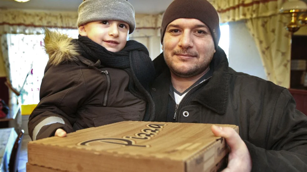 Treårige Ahmed och hans pappa Mehti, båda med efternamnet Saad, har precis fått sina varma pizzor och nu gäller det att snabbt ta sig hem. Bild: MIKAEL SVENSSON