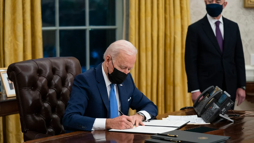 USA:s president Joe Biden skriver under nya presidentdekret medan landets nytillträdde minister för inrikes säkerhet, Alejandro Mayorkas, tittar på.