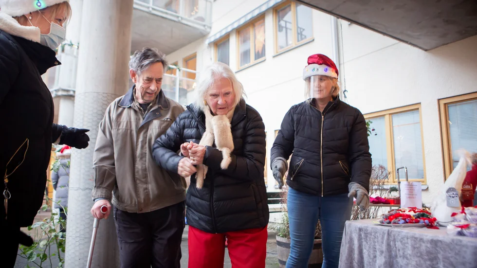 Stig Andersén ger Karin Pettersson en stödjande hand på väg till marknadsbordet i Pjäsens trädgård. Susanne Klasson och Ylva Utas visar vägen.