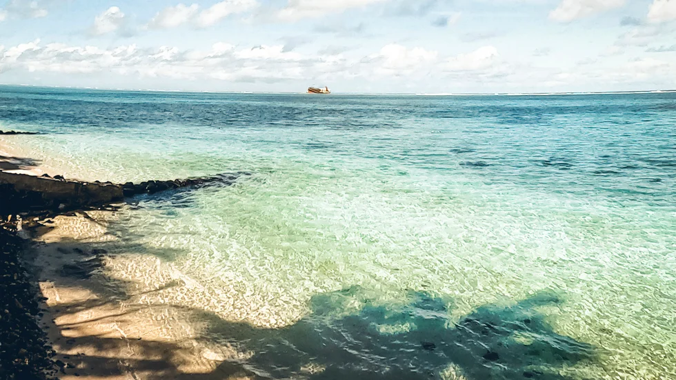 Fartyget som läcker olja skymtar från Mauritius strand.